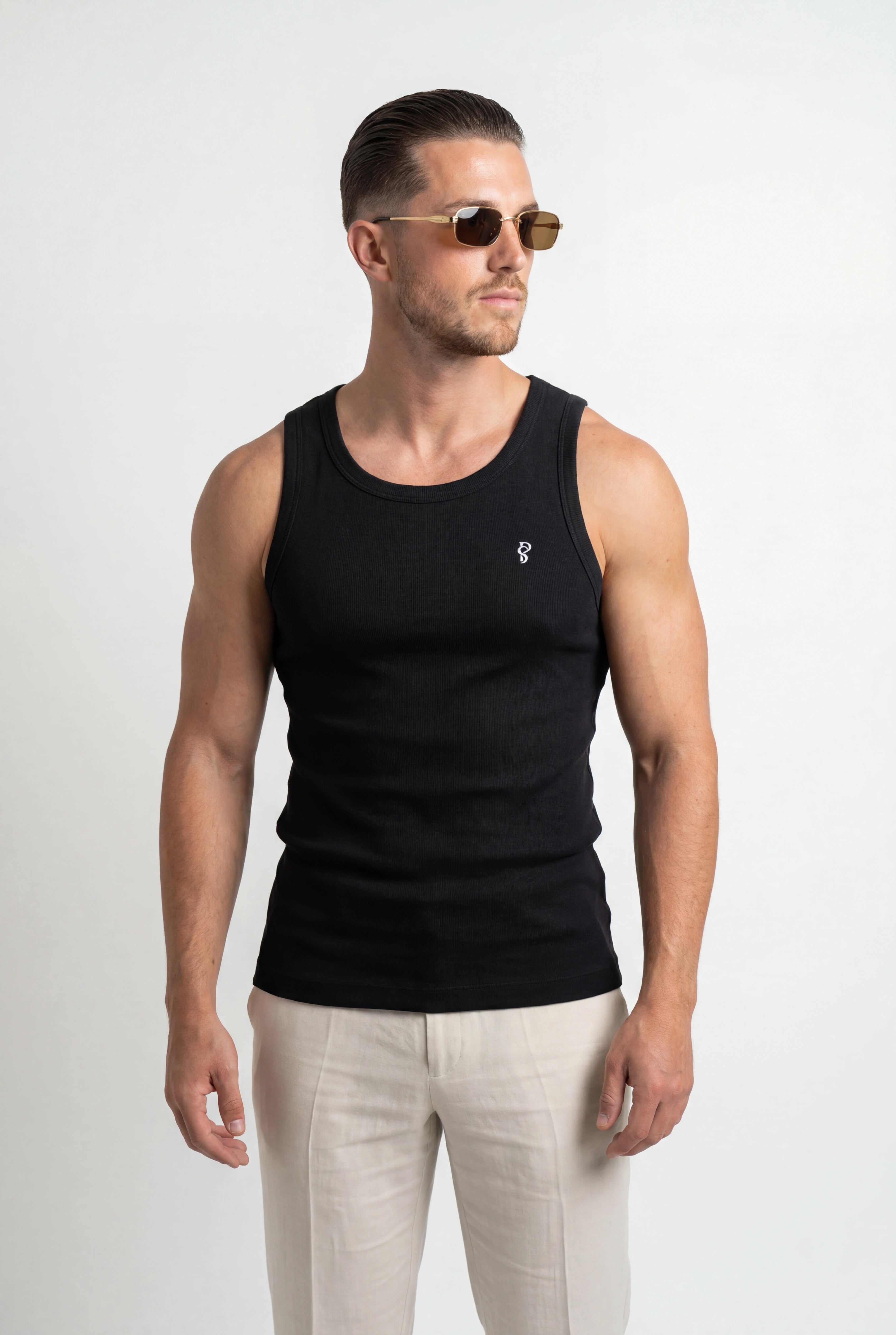 [Black] Man wearing a black tank top and light-colored pants on a white background